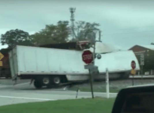 Watch a train plow through a semi truck stuck on the tracks